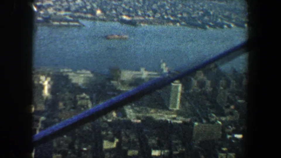 1960 New York City view of river, docks, and waterfront buildings, partly crossed by a dark diagonal observation structure.