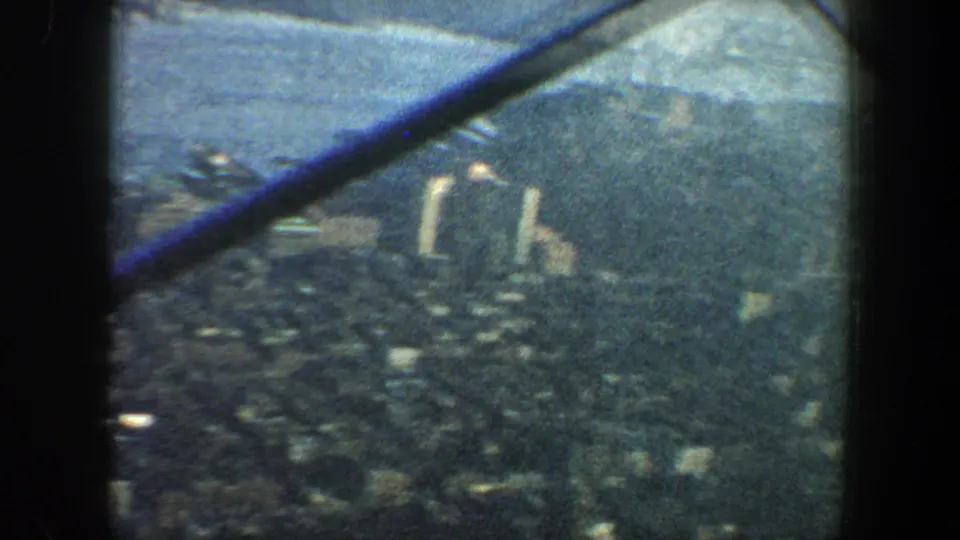 Elevated 1960 New York City view with waterfront buildings, river, distant land, and a diagonal observation-deck beam across the frame.