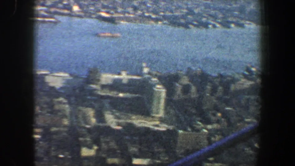 1960 New York City skyline and river from above, with dark frame edges and soft 8mm color grain.