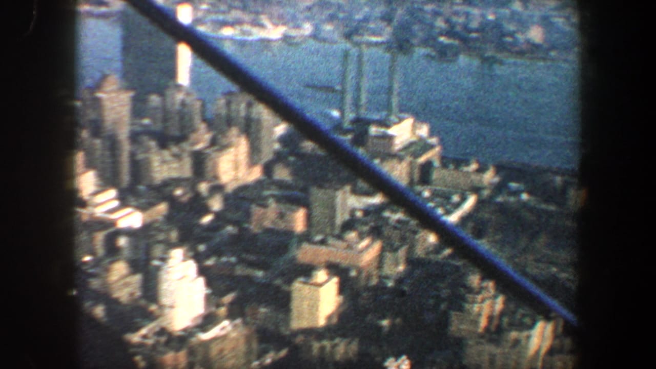 1960 New York City aerial view with dense buildings, waterfront, and aircraft structure visible across the frame.