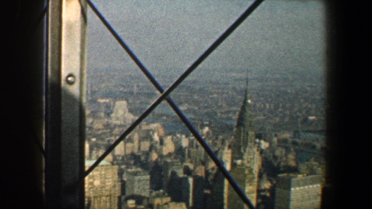 1960 New York City skyline with the Chrysler Building visible through an iron-barred high observation window.
