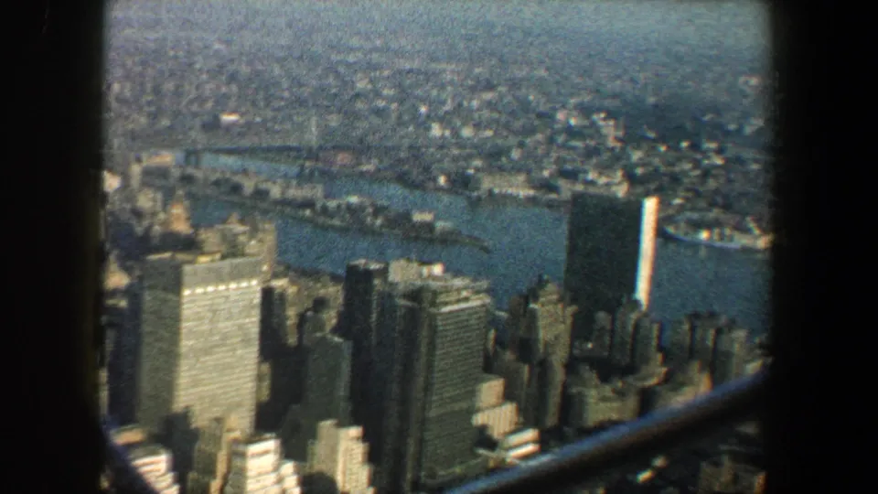 1960 New York City panorama with East River, Manhattan high-rises, distant bridges, and dark framing from a high vantage point.