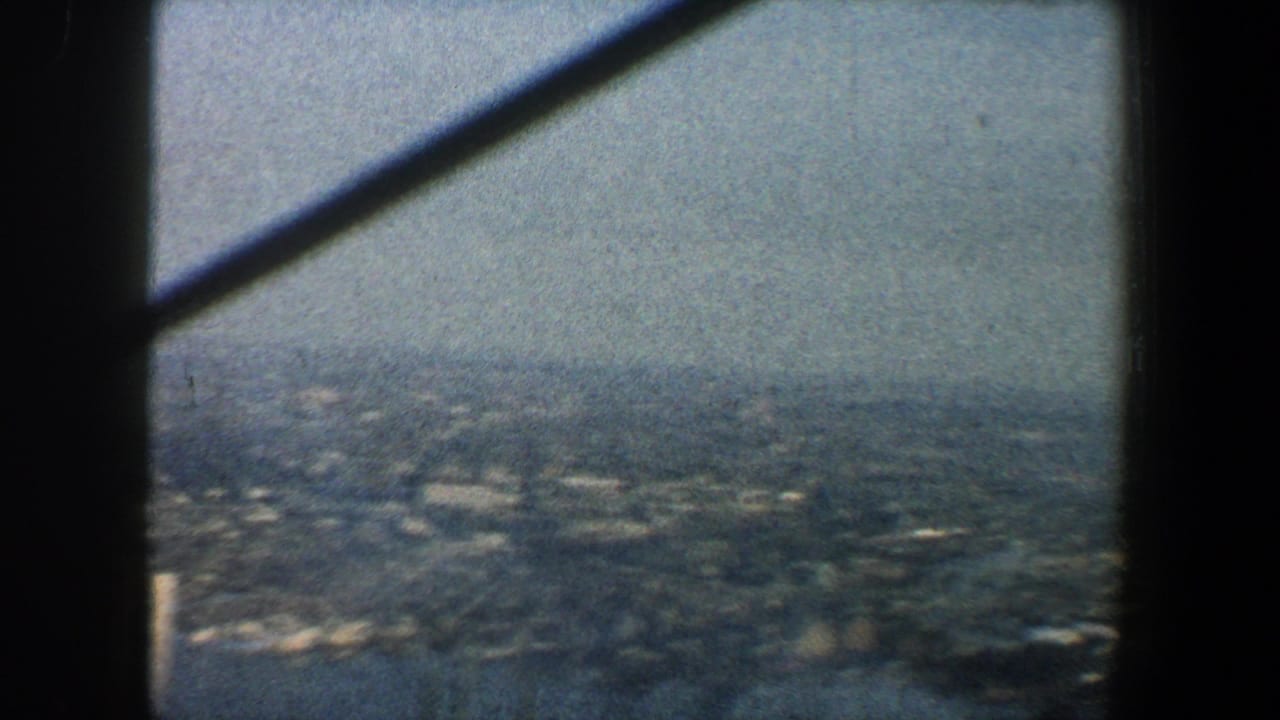 Distant city grid seen from above with dark tower beams crossing the frame.