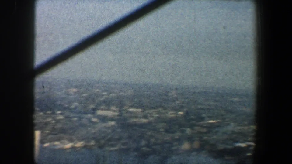 Elevated 1960 New York City view with a broad hazy cityscape beyond dark observation-tower supports.