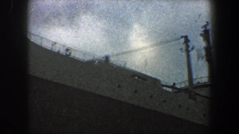 1960 New York City 8mm frame with ship railings, rigging lines, and vertical deck structures on a gray liner.