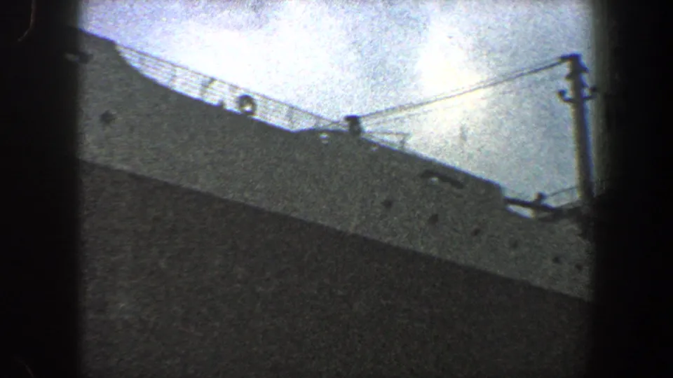1960 New York City 8mm view of a gray ocean liner deck with railing, life ring, and rigging lines.