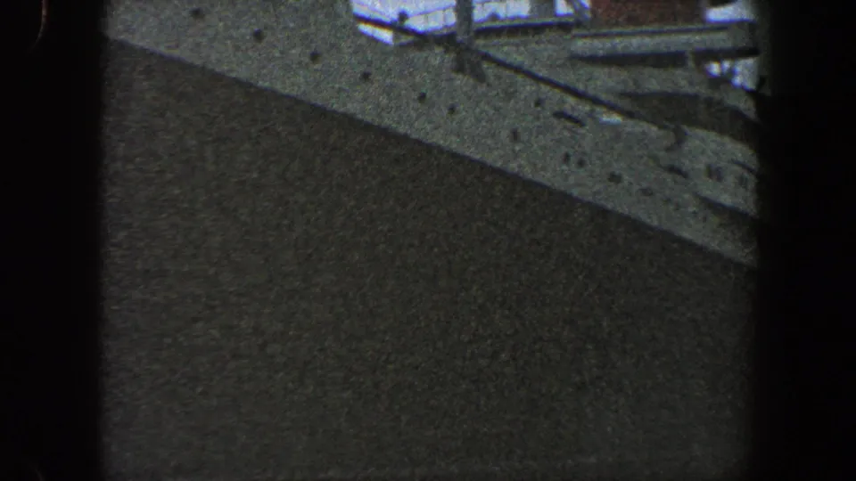 Close 8mm view of a large passenger ship's white hull and upper deck details in New York City, circa 1960.