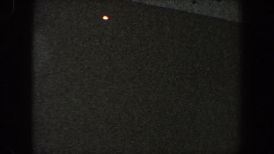 Final dark 8mm frame of the large passenger ship's side, with a small red point of light visible near the center.