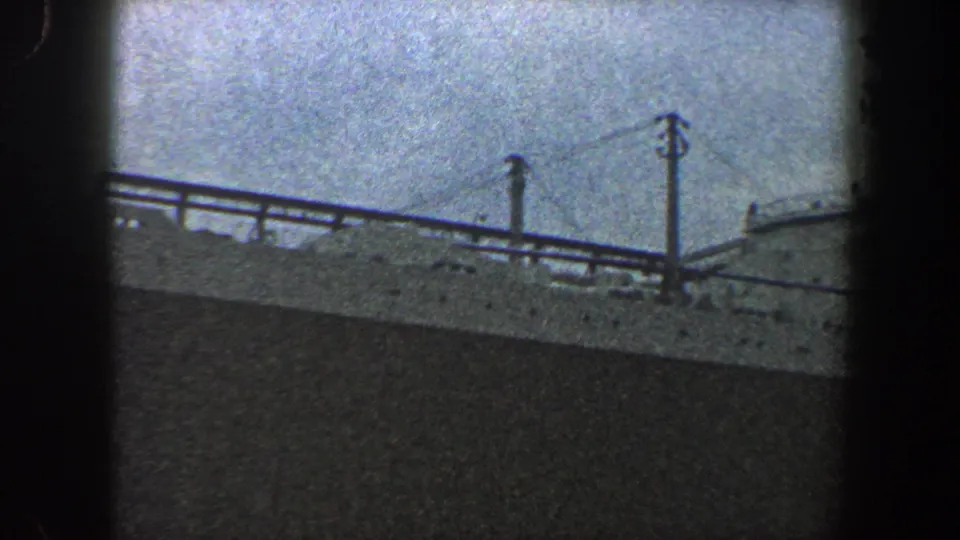 Final 8mm frame shows a hazy New York City ship view with railings, vertical posts, and a partial curved structure at the right edge.