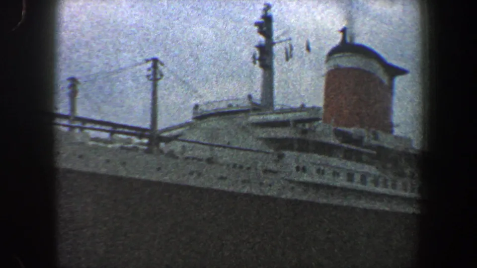 1960 New York City harbor view of a large ocean liner's superstructure, with mast details and a red funnel visible.