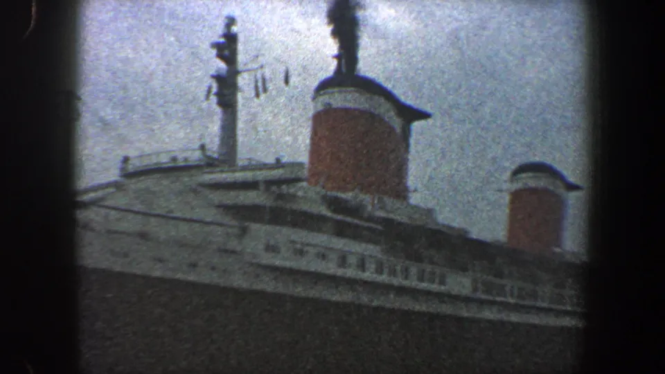 1960 New York City harbor shot showing two red funnels, upper decks and railings on a large ocean liner.