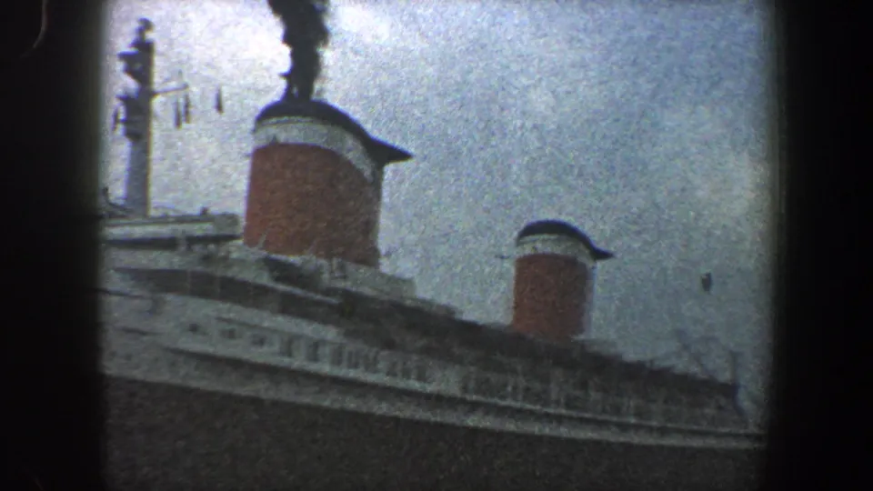1960 New York City harbor footage with the ocean liner's red funnels, railings and superstructure moving through a soft 8mm frame.