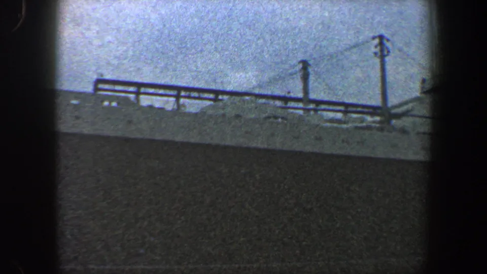 A later frame from the 1960 New York City home movie shows the liner's side with deck railings, small portholes, mast detail, and dark hull.