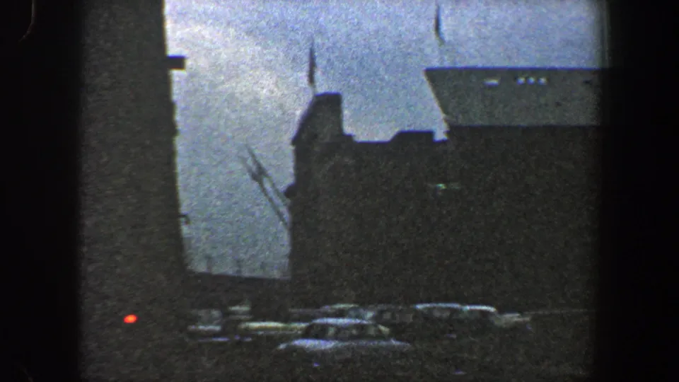 Large liner at a New York City port in 1960, with the ship's hull, upper structures, and parked cars visible below.