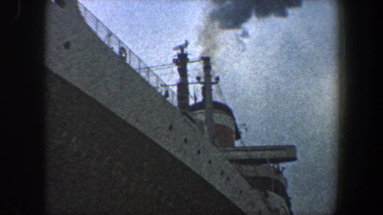 Ocean liner bow and upper deck details seen from below with smoke in the sky.