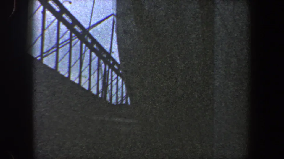 1960 New York City 8mm frame showing a close, low-angle view of a large grey ship hull and upper railing under overcast sky.