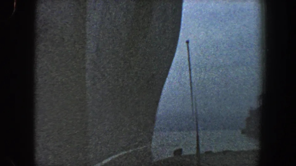 New York City harbor footage from 1960 showing a curved ship hull edge, pale sky, thin antenna, and faint low waterfront or deck edge.