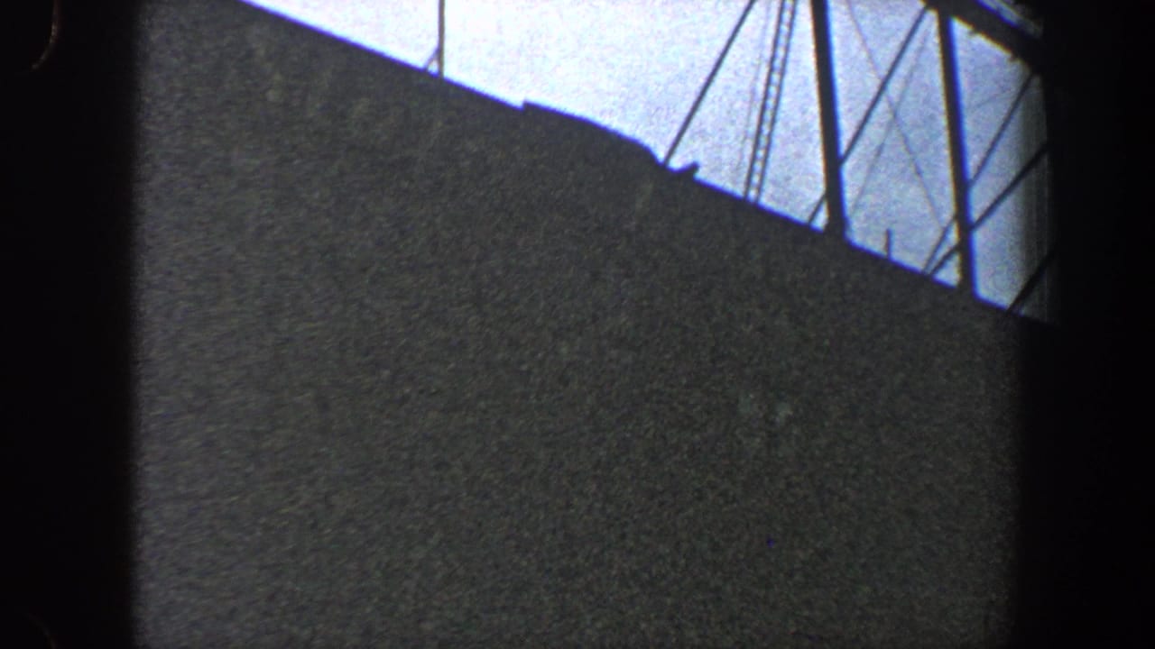 Large dark wall or structure with overhead supports and cables in silhouette.