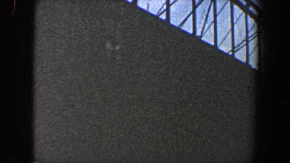 8mm view of a dark urban structure with diagonal framework and cables silhouetted against the sky in New York City, 1960.