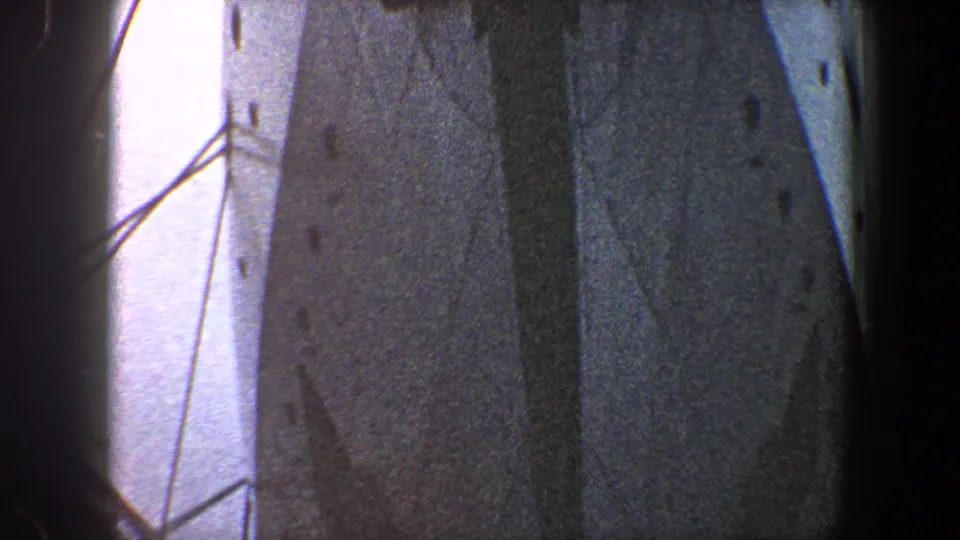 1960 New York City 8mm frame looking up along tall bridge steel plates, diagonal braces, and pale sky.