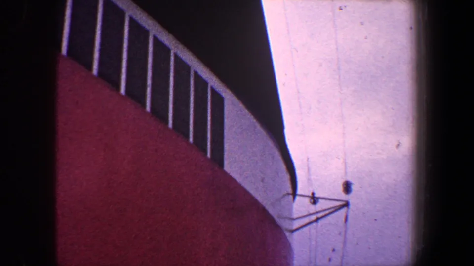 1960 New York City 8mm frame showing a close low-angle view of a red and white industrial or bridge-like structure with railings.