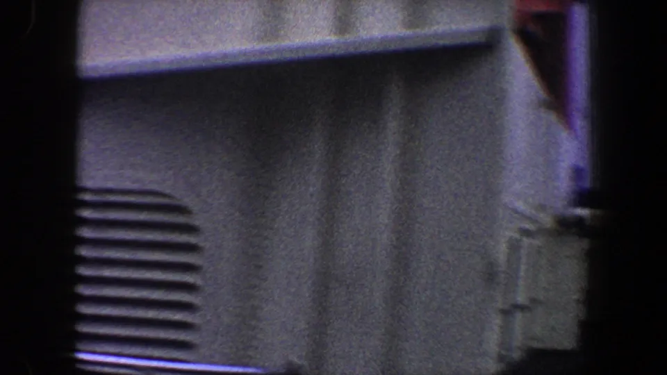 1960 New York City industrial exterior detail showing a wall, louvered vents, piping, and dark film-frame edges.