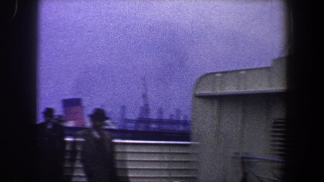 Silhouetted passengers in hats and coats stand along a boat deck railing in 1960 New York City home-movie footage.