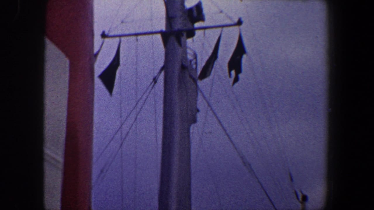 1960 New York City home-movie frame showing a passenger ship mast with flags, red funnel, vents, and upper deck details.