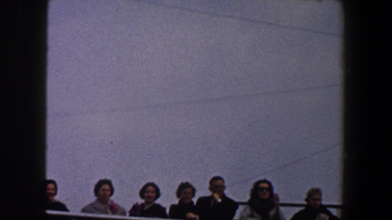 Adults standing behind a railing under a gray-blue sky.
