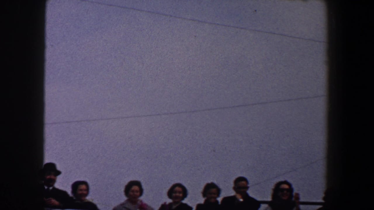 Group of adults lined along a railing, including a man in a dark hat.