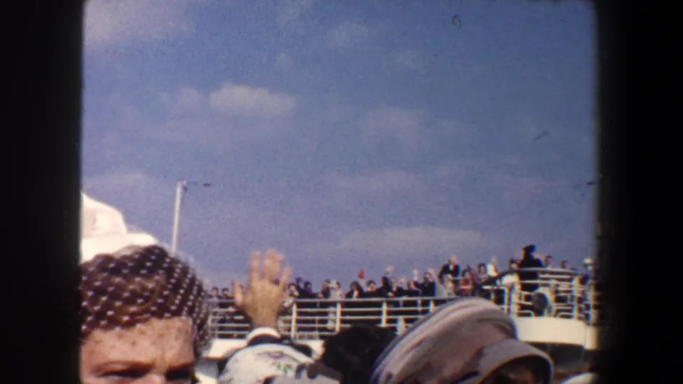 1960 New York City 8mm frame with a nearby passenger partly obscuring a waving boat-deck crowd.