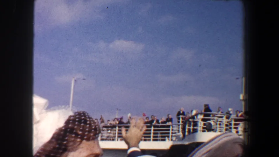 1960 New York City boat departure scene with passengers on deck and a foreground woman in a netted hat raising her hand.