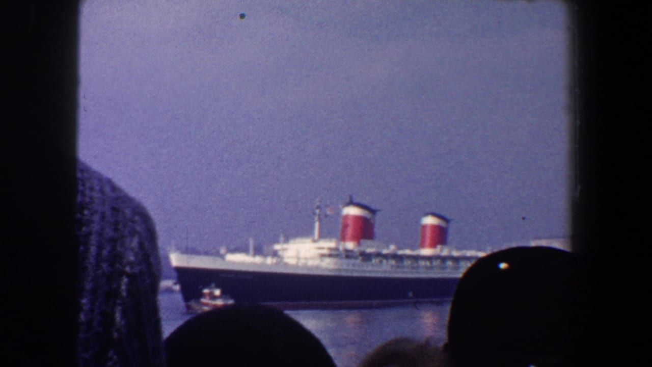 Ocean liner and small tugboat visible beyond dark window framing and onlookers.