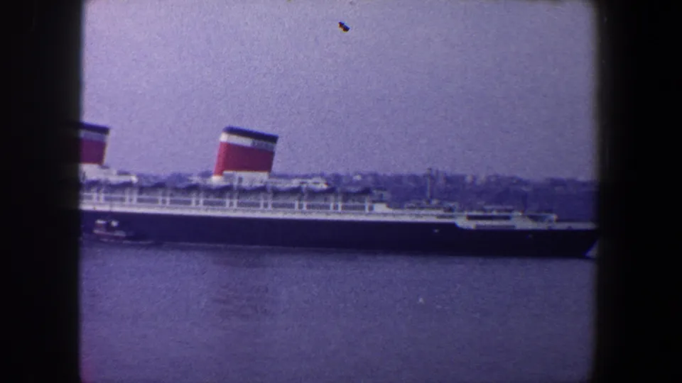 1960 New York City harbor frame with the Queen Mary, a small boat and a dark window mullion in view.