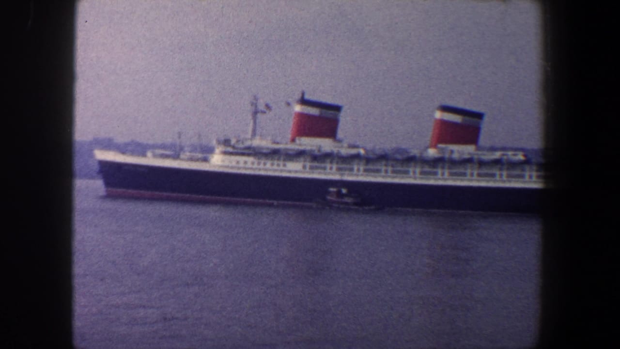 Large two-funnel ocean liner on harbor water with a small tugboat nearby.