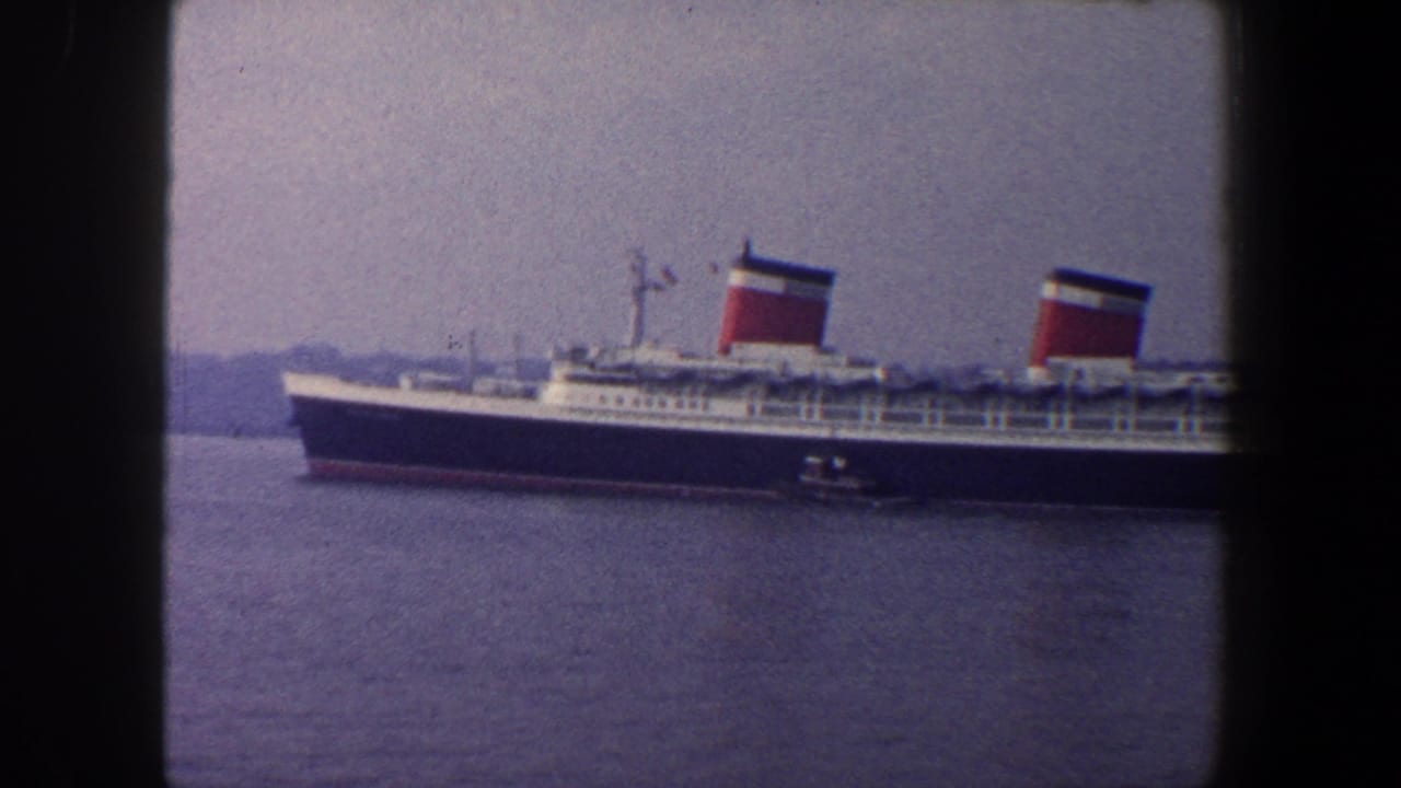 Ocean liner with two red-and-white funnels crossing the frame above harbor water.