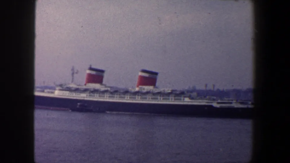 1960 New York City home-movie still showing a passenger liner nearing the right edge of the harbor frame.