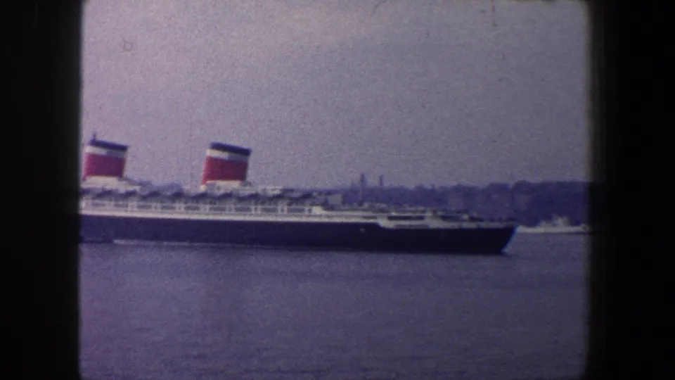 A broadside harbor view shows the large liner under an overcast sky, with New York City location supported by clip metadata.