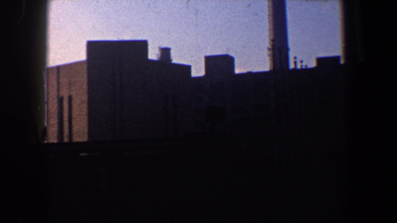 Dark industrial waterfront buildings silhouetted against a pale sky.