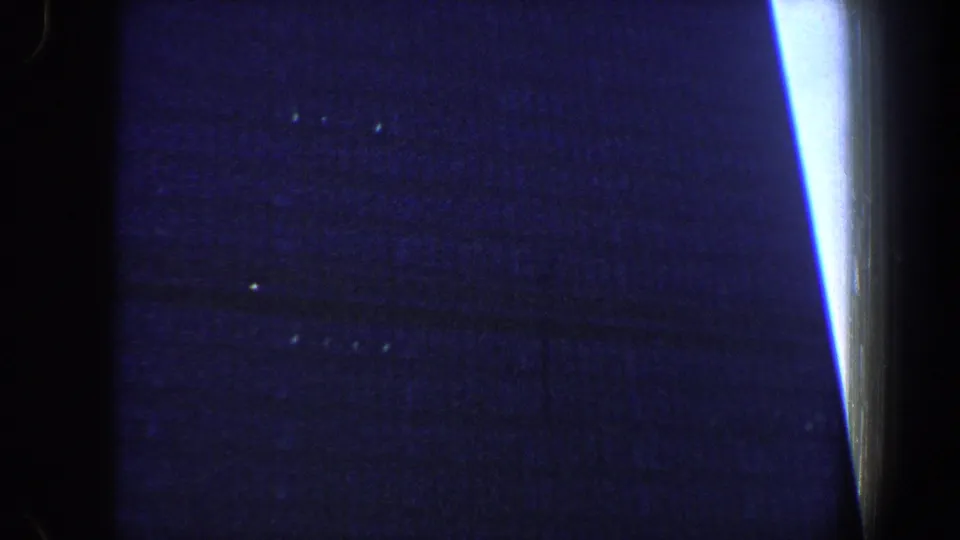 Dark blue 8mm frame from the New York City clip with a bright vertical light streak and obscured architectural forms.