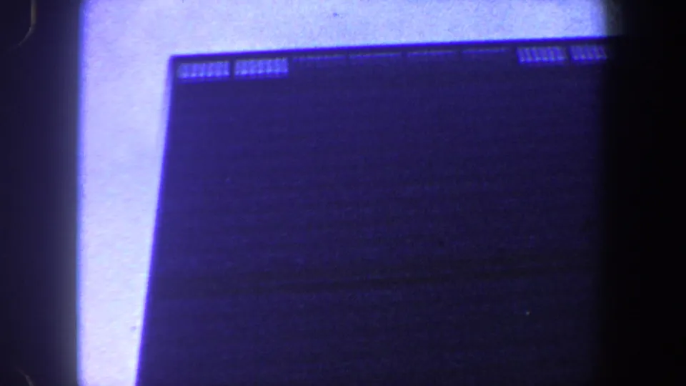 Final blue-tinted frame showing a dark multi-story building surface, faint windows, and a bright vertical light band.