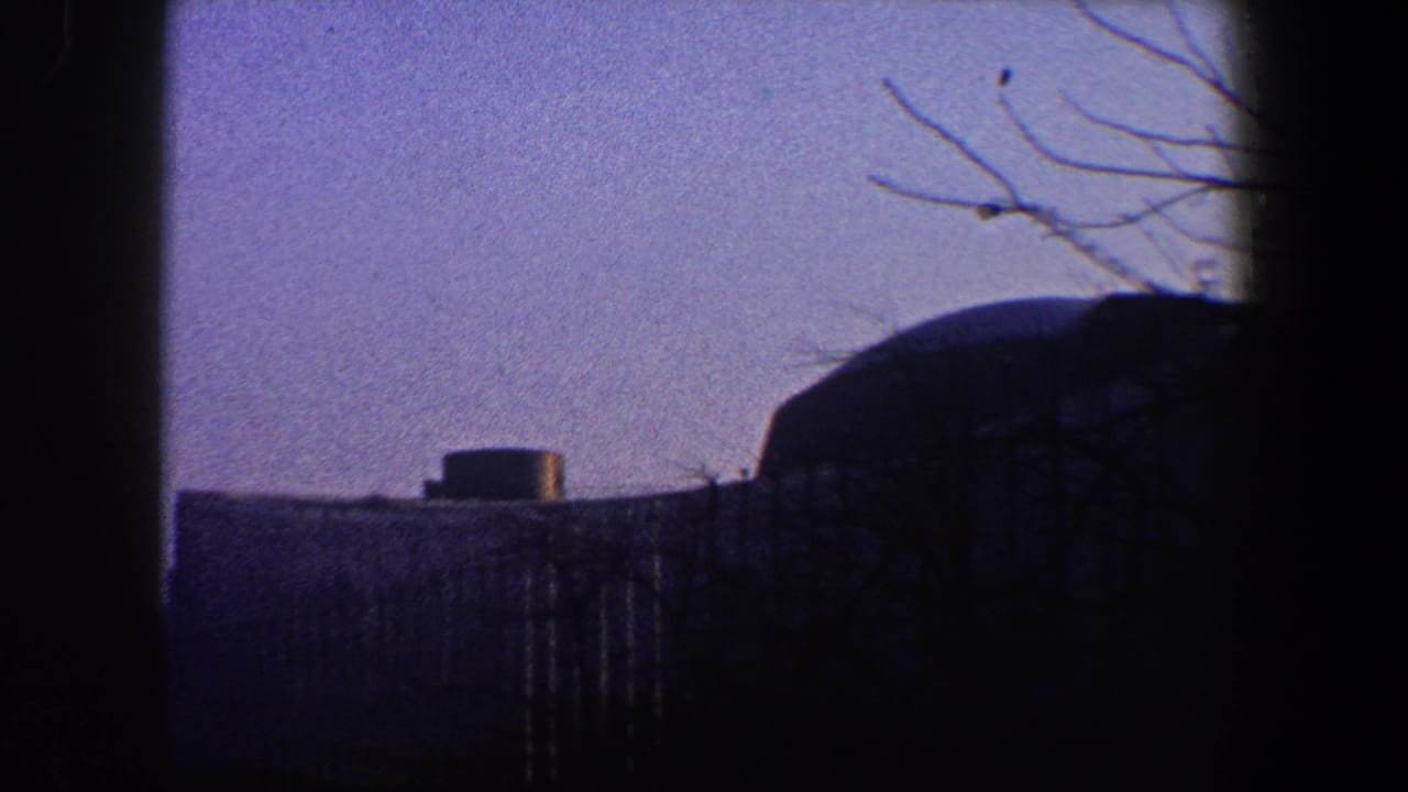 Hazy skyline with a domed roof at right and a low building with a rooftop cylinder.
