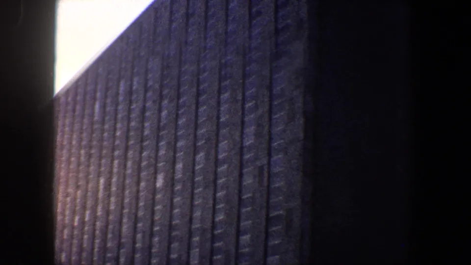Low-angle 8mm frame of a vertically striped New York City building exterior under bright sky.