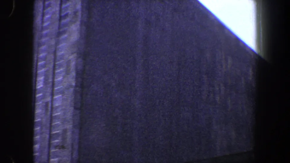 High-contrast 8mm view of a shadowed New York City building wall beneath a diagonal wedge of bright sky.