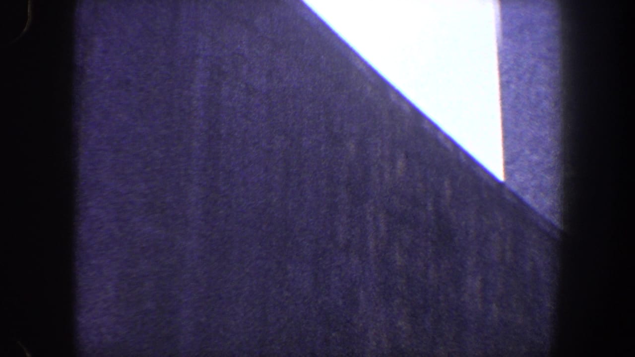 Low-angle view of a dark modernist building facade against a bright sky.
