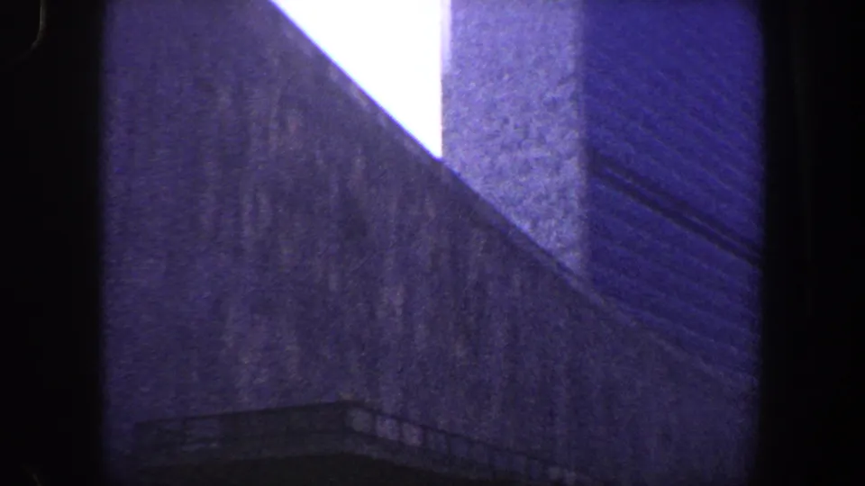 Low-angle 1960 New York City view of a tall modernist building face, vertical wall planes and a small rail-like detail near the base.