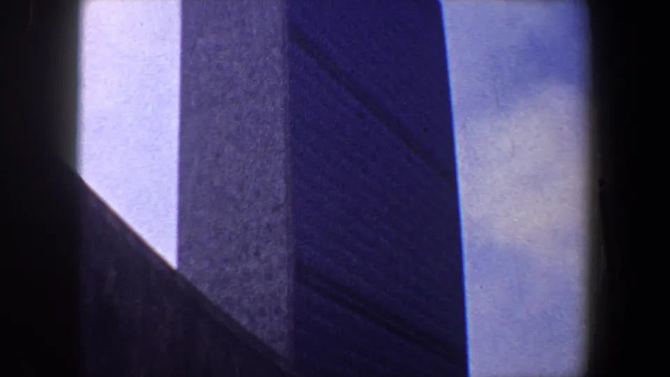 Late-frame view from 1960 New York City showing a modernist building corner, vertical wall planes and bright sky at the edges.
