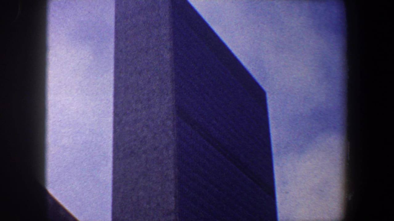 Tall dark skyscraper against pale blue sky with heavy film borders.
