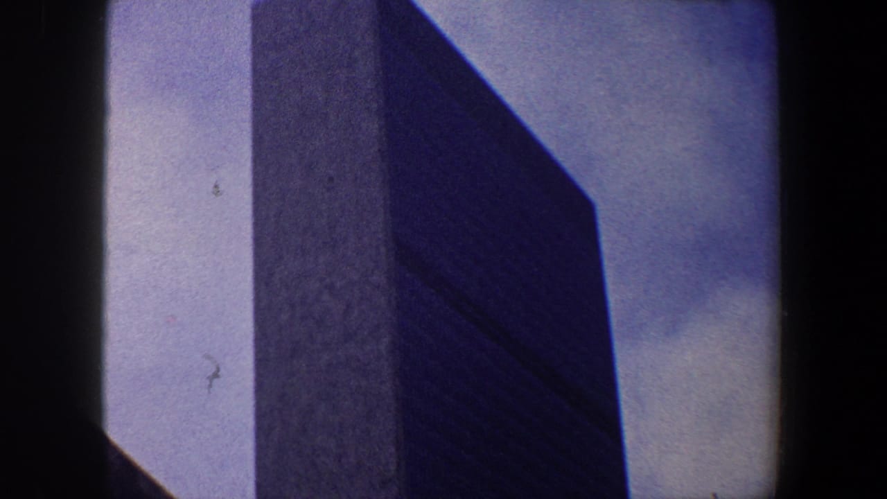 Upper skyscraper facade framed by sky and dark film borders.