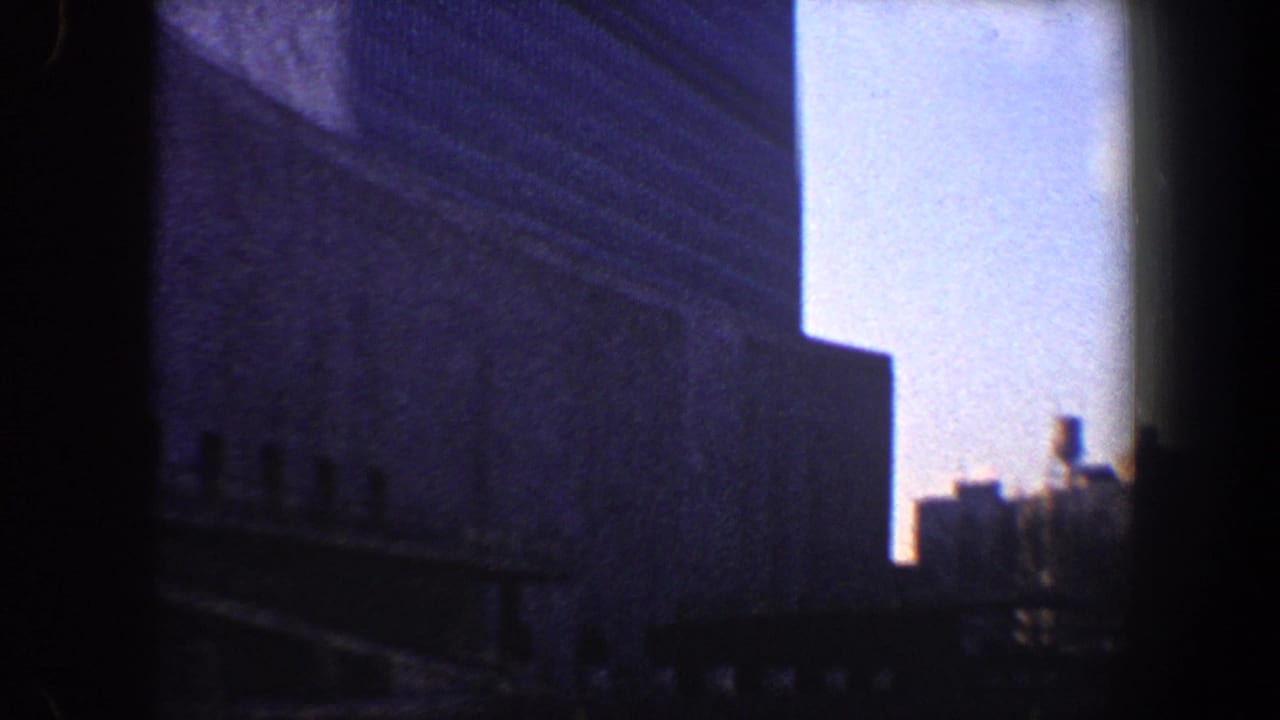 Dark-framed view of tall building facades with pale sky between them.